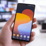 Kişinin elinde modern tasarımlı OnePlus 12 akıllı telefon, canlı ekran ve minimal teknoloji çalışma alanı arka planıyla.